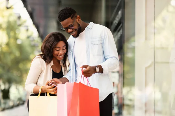 Gelukkig zwart paar holding shopping tassen kijken in — Stockfoto