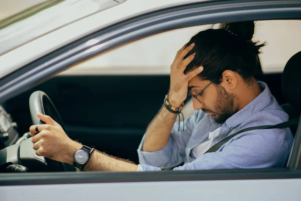 Estressante médio-oriental cara dirigindo carro, tocando sua cabeça — Fotografia de Stock