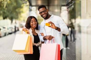 Kredi kartı tutan mutlu siyah çiftin portresi.