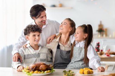 Mutlu aile ve çocuklar mutfakta birlikte poz veriyor, Noel ya da Şükran Günü için yemek hazırlıyorlar.