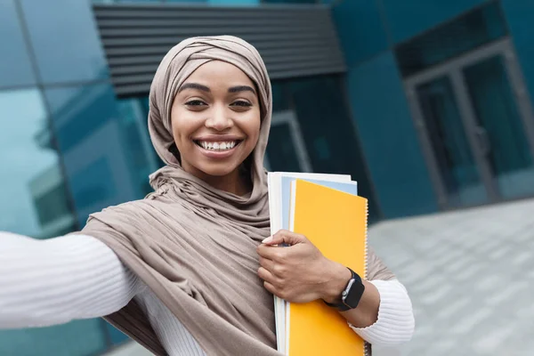 Örülök, hogy boldog szép muszlim afro-amerikai lány diák hidzsáb könyvekkel néz webkamera és fotót készít — Stock Fotó