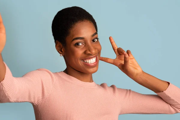 Glada ung svart kvinna tar selfie och Gesturing fred vid kameran — Stockfoto