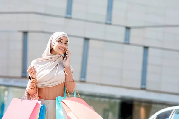 Şehir konseptinde alışverişkolik. Alışveriş merkezinin yakınında alışveriş torbalarıyla yürüyen, telefonla konuşan, satışları seven bir kadın. — Stok fotoğraf