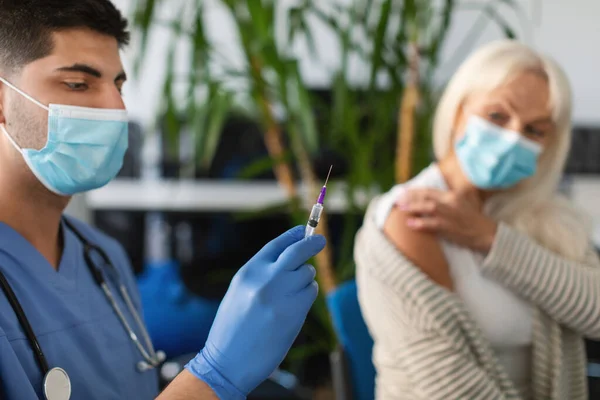 Senior Lady sendo vacinado contra o Coronavirus sentado no centro médico — Fotografia de Stock