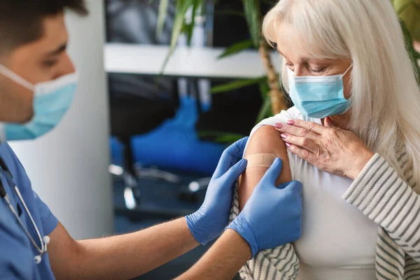 Senior Lady kapok védőoltás ellen Covid, orvos alkalmazása vakolat — Stock Fotó