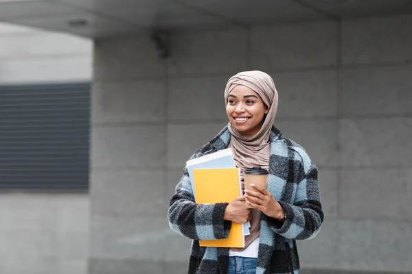 Feliz estudiante afroamericana bastante linda en hijab y abrigo con libros y taza de café listo para estudiar — Foto de Stock