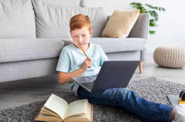 Bilgisayarlı mutlu öğrenci evde ödev yapıyor.