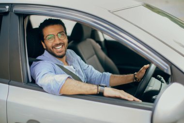 Sağdan direksiyon sallayan neşeli Arap adam.