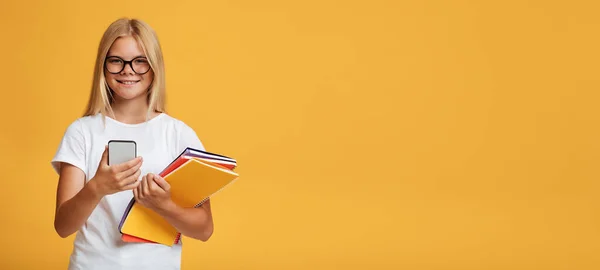Wesoły słodkie nastolatek biały blondynka dziewczyna w okulary z notebooki wykorzystuje telefon do nauki — Zdjęcie stockowe