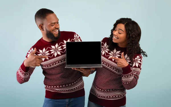 Grandes descontos e vendas para o Ano Novo. Entusiasmado casal afro-americano apontando para laptop com tela em branco — Fotografia de Stock