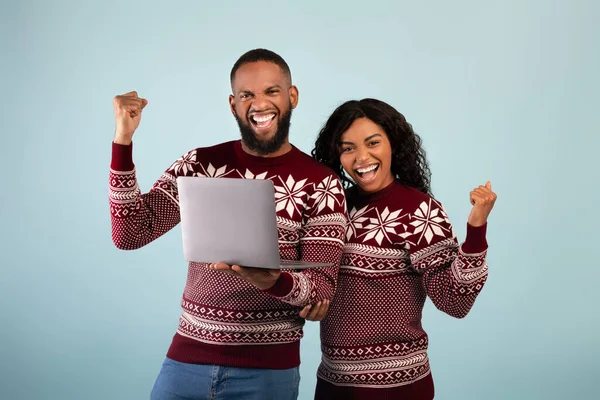 Wow offre de Noël. Heureux couple afro-américain célébrant le succès avec ordinateur portable, fond bleu studio — Photo