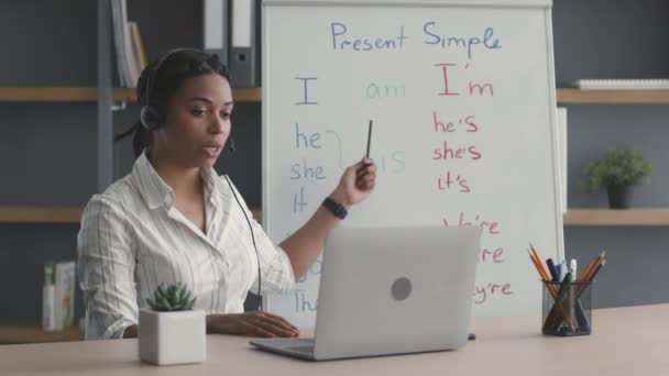 Online μαθήματα αγγλικών για αρχάριους. Νεαρή Αφροαμερικάνα δασκάλα βίντεο συνομιλίας με μαθητή μέσω φορητού υπολογιστή — Αρχείο Βίντεο