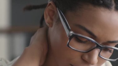 Sabit iş sorunları. Üzgün Afro-Amerikan bayan yönetici işyerinde ağrılı boynuna masaj yapıyor, acıdan kıvranıyor.