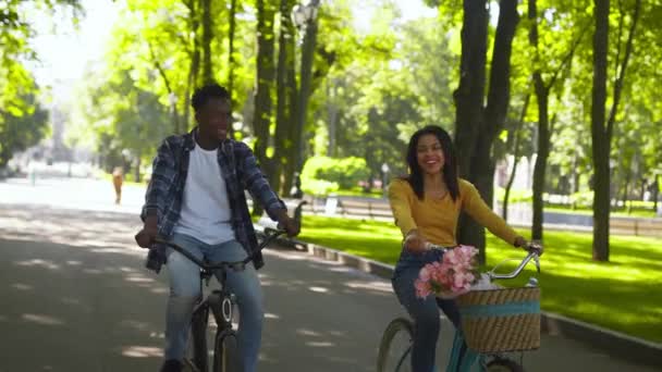 Koncept volného času a aktivního životního stylu. Přední pohled na mladé africké americké páry nebo přátelé na koni jejich kola v městském parku — Stock video