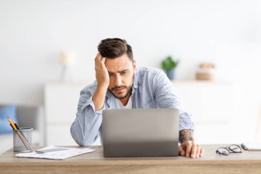 Bağımsız stres. Erkek serbest yazar işten sonra evde dizüstü bilgisayar başında yorgun, projeyle ilgili sorunları var, iş yerinde oturuyor