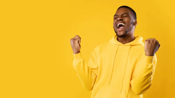 Emocional hombre negro gritando sacudiendo puños celebrando el éxito, fondo amarillo —  Fotos de Stock