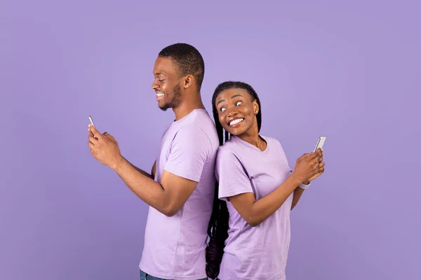 非洲裔美国人夫妇使用智能手机，紫色工作室墙壁 — 图库照片
