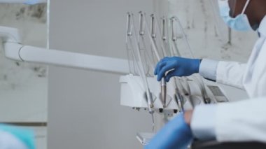 Tanımlanamayan siyah dişçi sıkıcı makineyi alıyor ve kadın hasta dişlerini tedavi etmeye başlıyor.