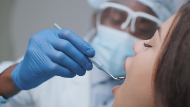 Patiente afro-américaine assise à la clinique dentaire, dentiste noir faisant des recherches sur les dents — Video