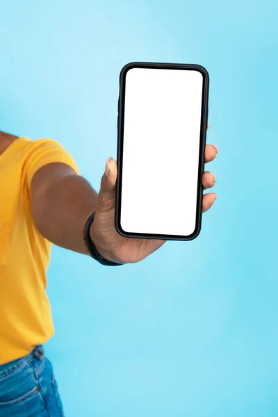 Donna nera irriconoscibile che mostra smartphone con mockup, promozione di applicazioni o siti web, sfondo blu — Foto Stock