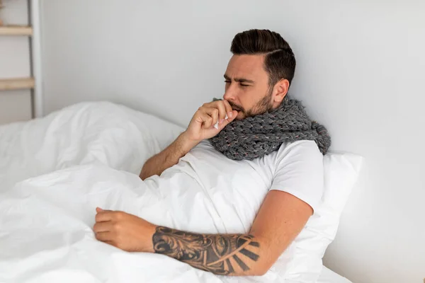 Κόβιντ-19. Άρρωστος τύπος που βήχει, υποφέρει από πνευμονία από κορωναϊό, κάθεται στο κρεβάτι κάτω από κουβέρτα, ελεύθερος χώρος — Φωτογραφία Αρχείου