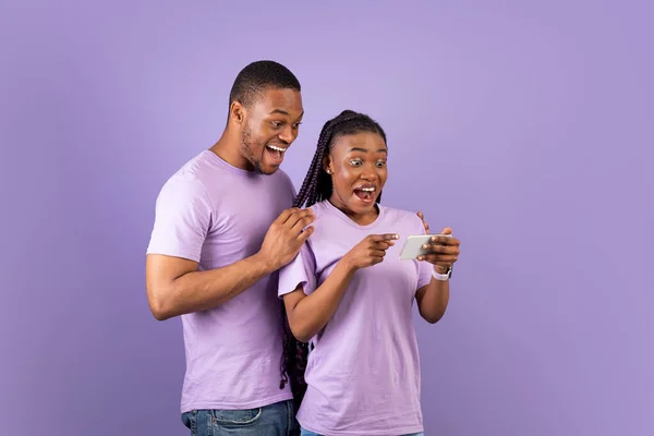 Portrait de couple noir surpris utilisant un smartphone — Photo