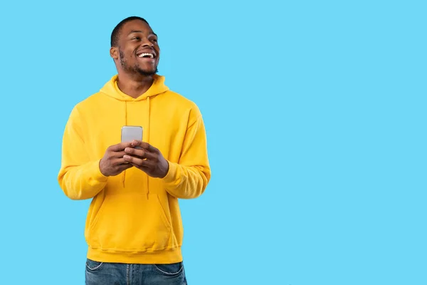 Joyful African Man Using Cellphone Texting Looking Aside, Blue Background — Stok Foto