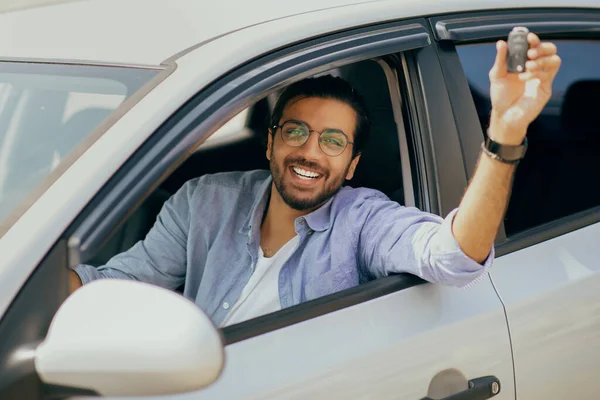 Fröhlich indisch langhaarige Kerl zeigt Autoschlüssel und lächelt — Stockfoto