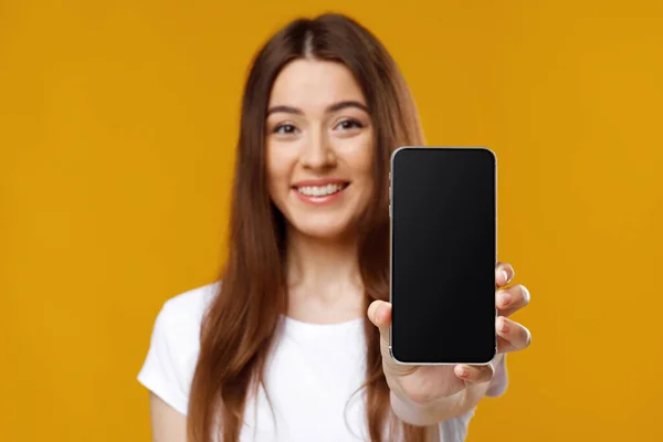 Primer plano de la joven feliz mostrando el teléfono inteligente con la pantalla vacía — Foto de Stock