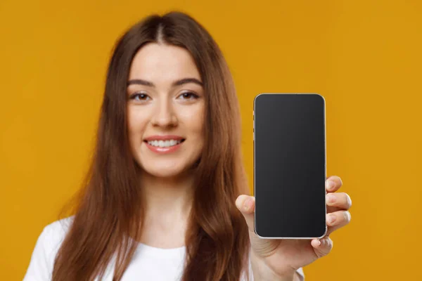 Primer plano de la hermosa mujer joven mostrando el teléfono celular con la pantalla vacía — Foto de Stock