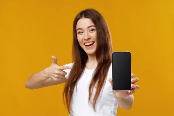 Glada söt dam pekar på mobiltelefon med tom skärm — Stockfoto