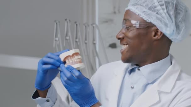 긍정적 인 장난기가 있는 아프리카 계 미국인 치과 의사 플라스틱 턱 과찡그린 자세로 치과 병원에서 장난을 치고 있는 — 비디오