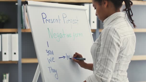 Joven mujer afroamericana profesora escribiendo reglas gramaticales en inglés Present Perfect negative form on whiteboard — Vídeo de stock