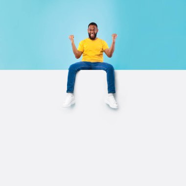 Reklam pankartı maketi. İlan için yeri olan boş beyaz reklam panosunun tepesinde oturan siyahi adam EVET hareketi yapıyor.