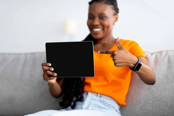 Internetköp. Glad svart kvinna pekar på surfplatta med mockup för shopping app eller webbdesign hemma — Stockfoto