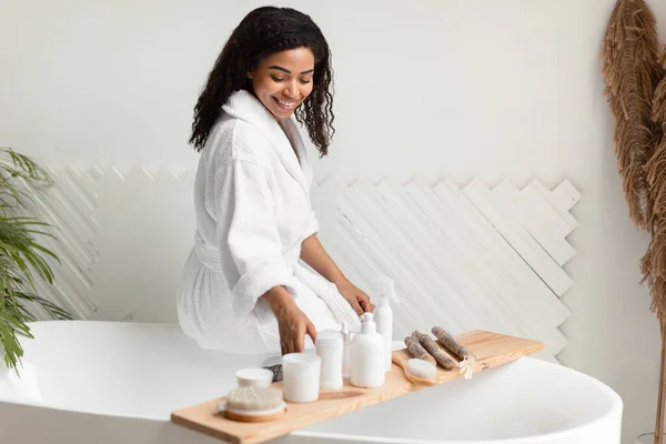 Afrikaanse dame kiezen natuurlijke cosmetische producten Zittend in de badkamer Binnenshuis — Stockfoto