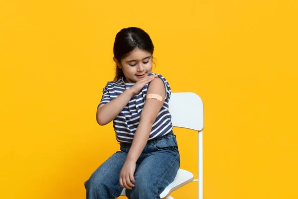 Vacunación Covid-19. Niña vacunada mirando el brazo con yeso después de la inyección — Foto de Stock