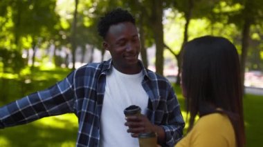 Mutlu Afro-Amerikan erkeği zevk alarak kız arkadaşıyla parkta konuşuyor, bisikletle dinleniyor ve kahve alıyor.