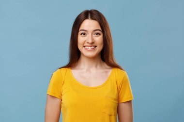 Mavi arka planda gülümseyen neşeli genç bayan.