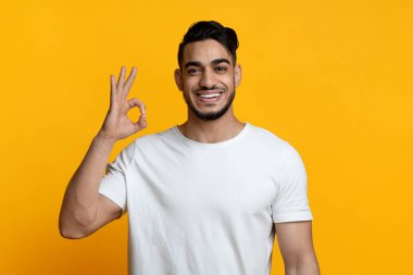 Neşeli Arap adam iyi jest yapıyor ve gülümsüyor.