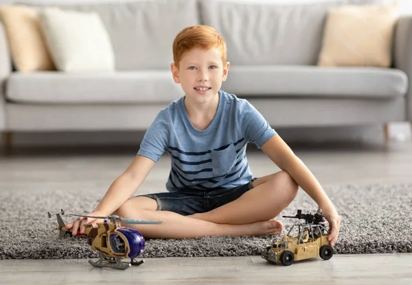 Niedliches Kind spielt mit Spielzeug Militärfahrzeuge zu Hause — Stockfoto