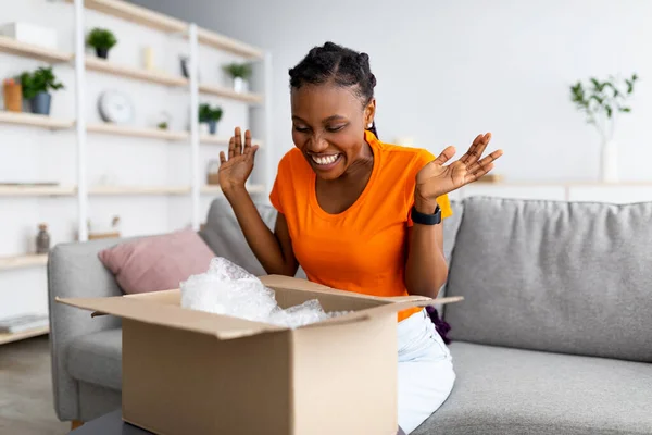 Túlságosan boldog Afro nő unbox karton csomag, érzelmes a sikeres vásárlás, elégedett a nagy vásárlás otthon — Stock Fotó
