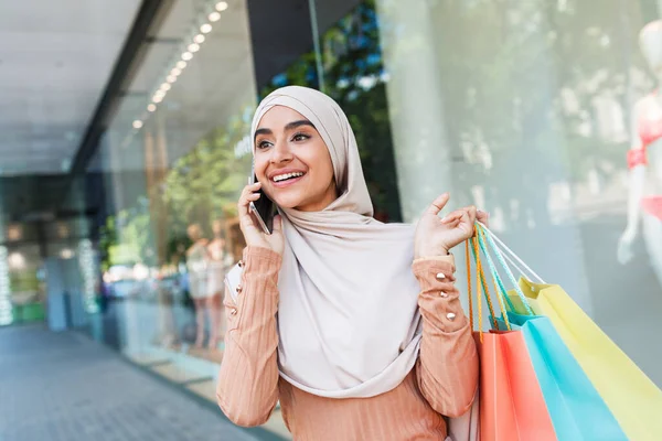 Mutlu, tesettürlü genç Arap kadın büyük indirimden bahsediyor, bir sürü paketle modern alışverişi seviyor. — Stok fotoğraf