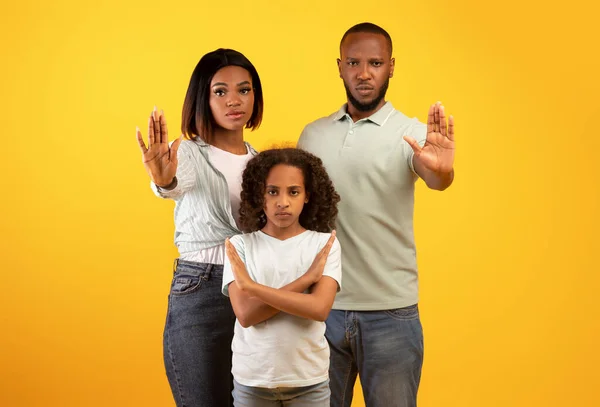 抗議、反対、否定のジェスチャー。停止標識を示すアフリカ系アメリカ人の両親と娘,黄色の背景 — ストック写真