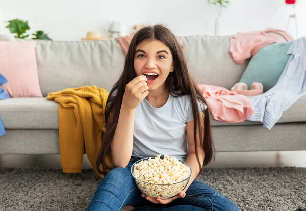 Cool indický dospívající dívka výdaje její volný čas sledování televize a jíst popcorn na podlaze doma — Stock fotografie