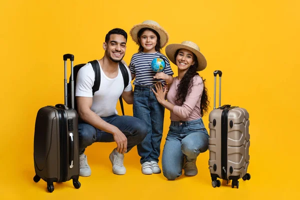 Voyage en famille. Joyeux parents arabes et petite fille avec des valises sur fond jaune — Photo