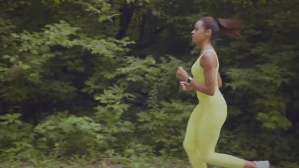 Allenamento sportivo. Giovane atleta afro-americana attiva che corre da sola nel parco pubblico, allenamento al mattino — Video Stock