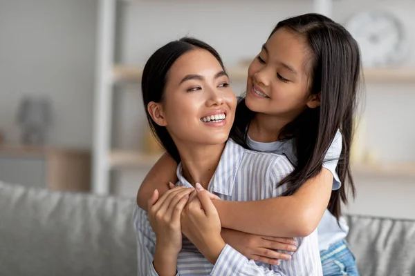 Концепция сближения и единения. Азиатские мама и дочь обнимаются и улыбаются, наслаждаются проведением времени вместе — стоковое фото