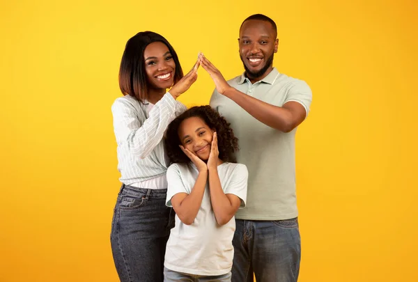 Familie zorg, bescherming en verzekering concept. Jonge zwarte ouders maken symbolisch dak van handen boven kleine dochter — Stockfoto