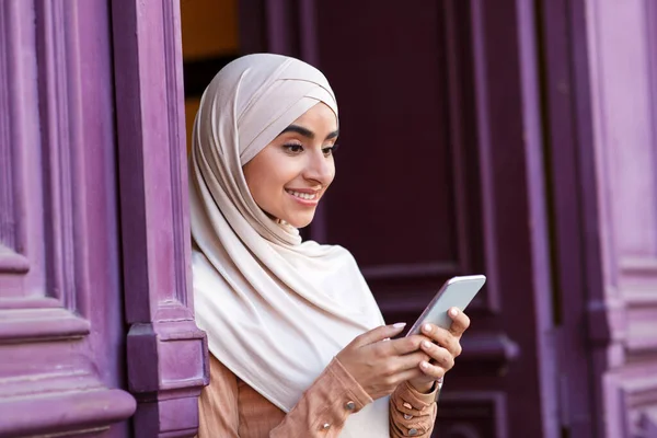 Mosolygó csinos fiatal muszlim arab nő hidzsáb élvezi a szabad időt a hétvégén, és ellenőrzi a szociális hálózatok — Stock Fotó